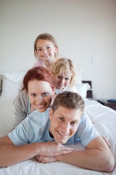 Playful family lying on each other on the bed