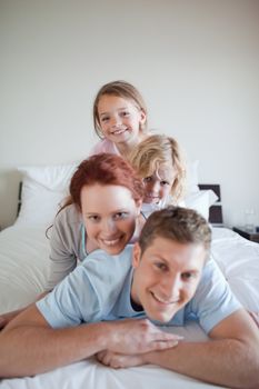Cheerful family lying on each other on the bed