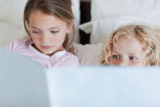 Girl reading a bed time story for her little brother
