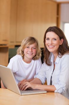Mother and her son with laptop in the kitchen