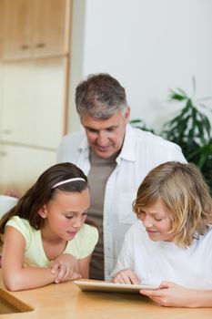 Boy with tablet showing things to his sister and father