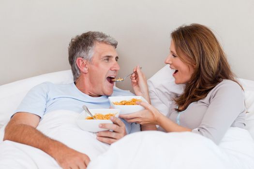 Mature couple eating cereals in their bed