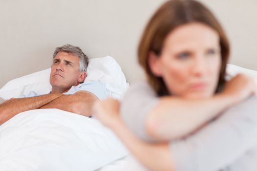 Sad man in the bed with his wife in the foreground