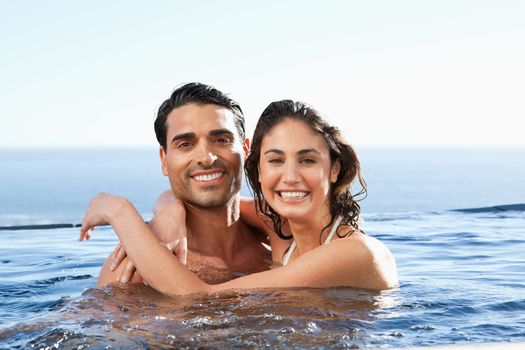 Smiling young couple embracing in the pool