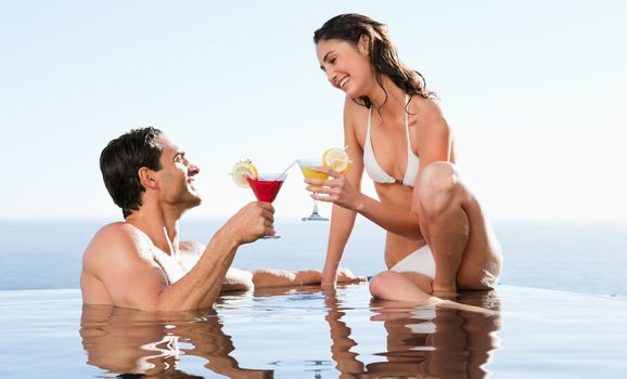 Happy couple having cocktails in the pool