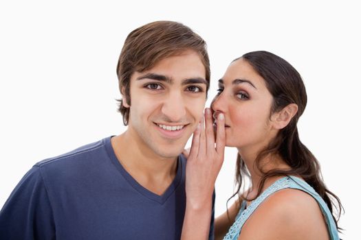 Young woman whispering something to her fiance against a white background