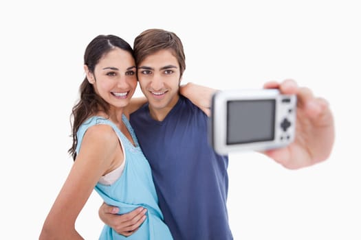 Young couple taking a picture of themselves against a white background