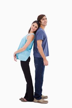 Portrait of a young couple standing back to back against a white background
