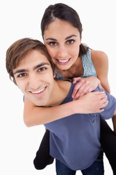 Portrait of a young man holding his girlfriend on his back against a white background