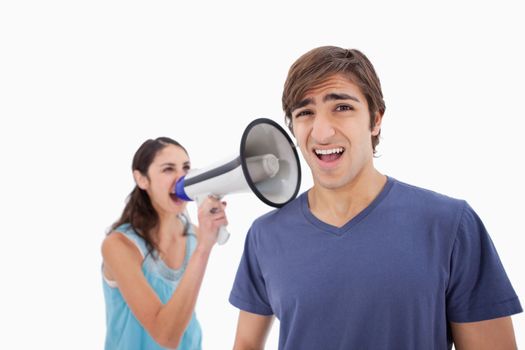 Woman yelling at her boyfriend through a megaphone against a white background