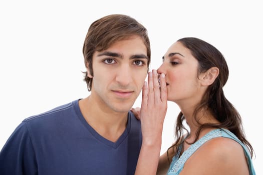Woman whispering something to her boyfriend against a white background