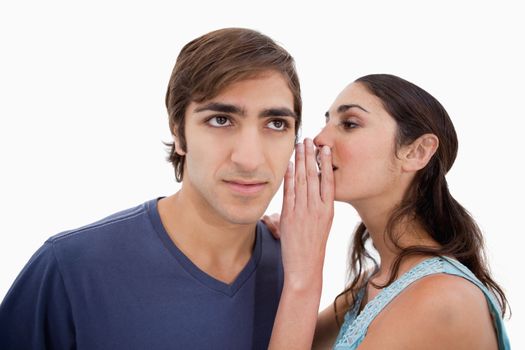 Woman whispering something to her fiance against a white background