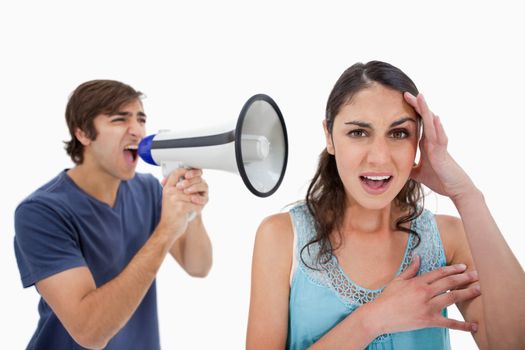 Man shouting at her girlfriend through a megaphone against a white background