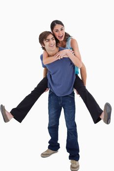 Portrait of man holding his girlfriend on his back against a white background