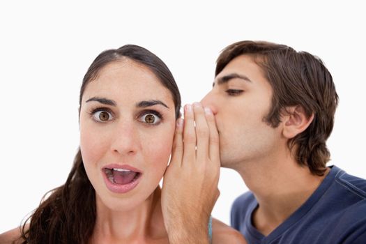 Man whispering something shocking to his fiance against a white background