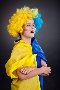 Football fan with a blue and yellow ukrainian flag painted on his face on black background