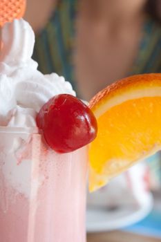 milkshake with a cherry and orange on the glass in the cafe shooting