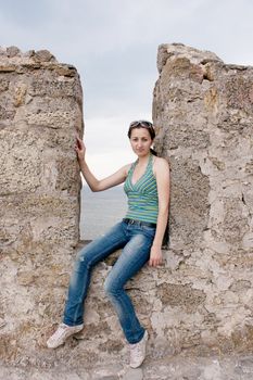 A girl sits in a niche of a stone wall photo