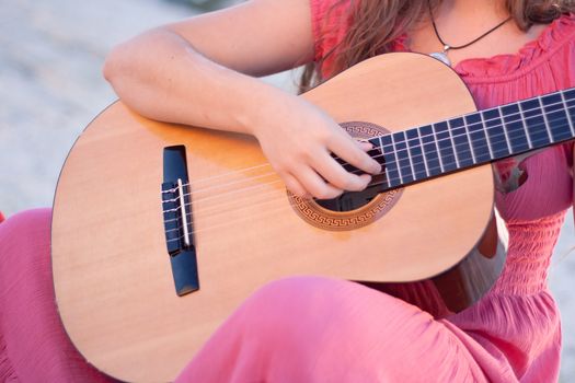 A girl in a dress playing a guitar shot on the nature