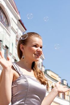 Beautiful girl with soap bubbles against a background of sky homes and shooting outdoors