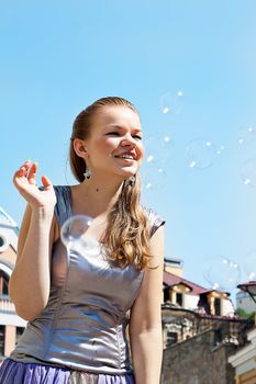 Girl with soap bubbles in the sky shooting on outdoors