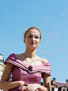 Girl with soap bubbles in the sky shooting on outdoors
