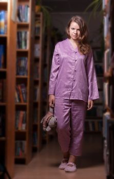 Girl in pajamas and slippers at night in the library survey in the interior