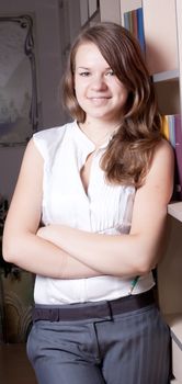 A girl in a library near a bookcase