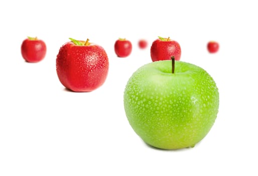 Green apple in front of red apples on white background
