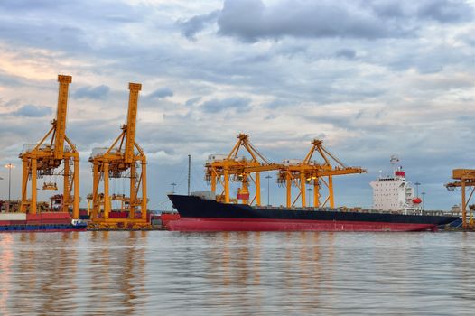 Container Cargo freight ship with working crane bridge in shipyard 