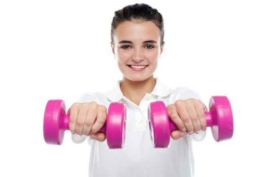 Image of smiling young girl posing with dumbbells in front of camera
