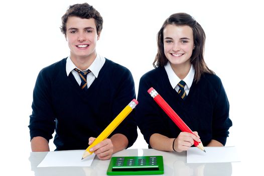 Studious students ready to take down the notes. Holding big pencil with calculator lying on desk