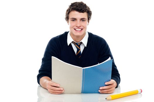Studious boy preparing for half yearly exams. Holding his notebook and reading