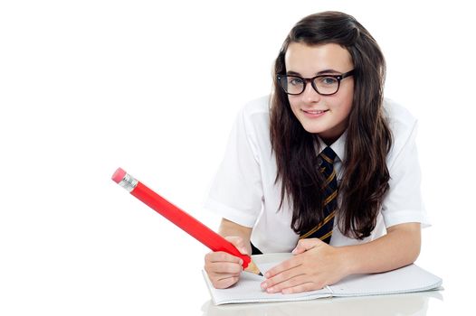 Bespectacled schoolgirl with long hair studying. Hiding her answers during examination