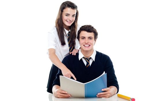 Girl pointing out the answer to her classmate. Cheerfully posing in front of camera