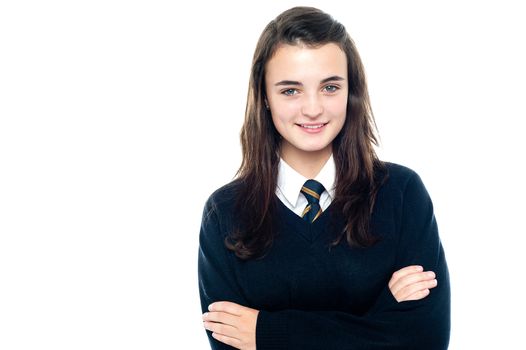 Confident young school child in uniform posing with folded arms