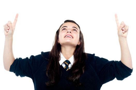 Excited young teenage girl looking and pointing upwards. All on white background