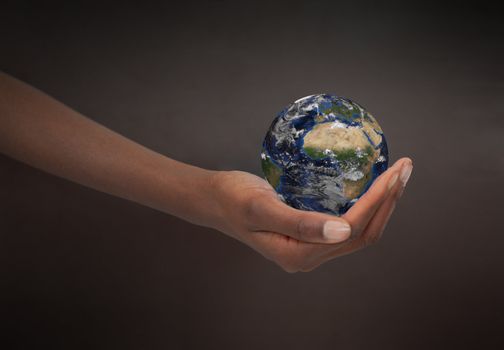 Feminine hand holding the Earth against a dark background