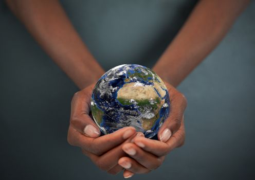 Feminine hands holding the Earth against a dark background