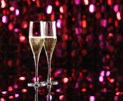 Two glasses of champagne, colored lights as background