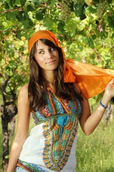 Beautiful girl dressed gypsy style in a vineyard with red and green grapes