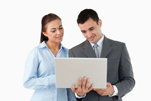 Young business partners looking at laptop against a white background
