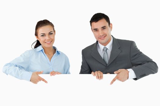 Business partners pointing at sign they are holding against a white background