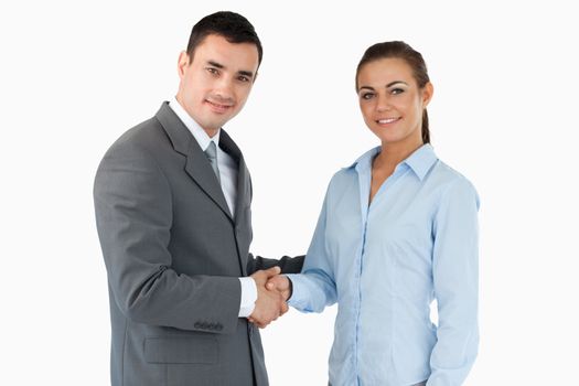 Smiling business partners closing a deal against a white background