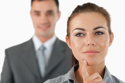 Close up of thoughtful businesswoman with colleagues behind her against a white background