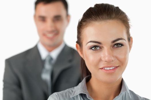 Close up of smiling businesswoman with colleague behind her against a white background