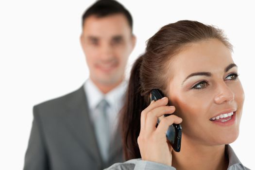 Close up of young businesswoman on the phone with colleague behind her against a white background