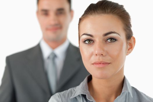 Close up of young businesswoman with colleague behind her against a white background