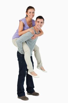 Young male carrying his girlfriend piggyback against a white background