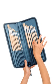 The woman chooses from a set of brushes one for drawing